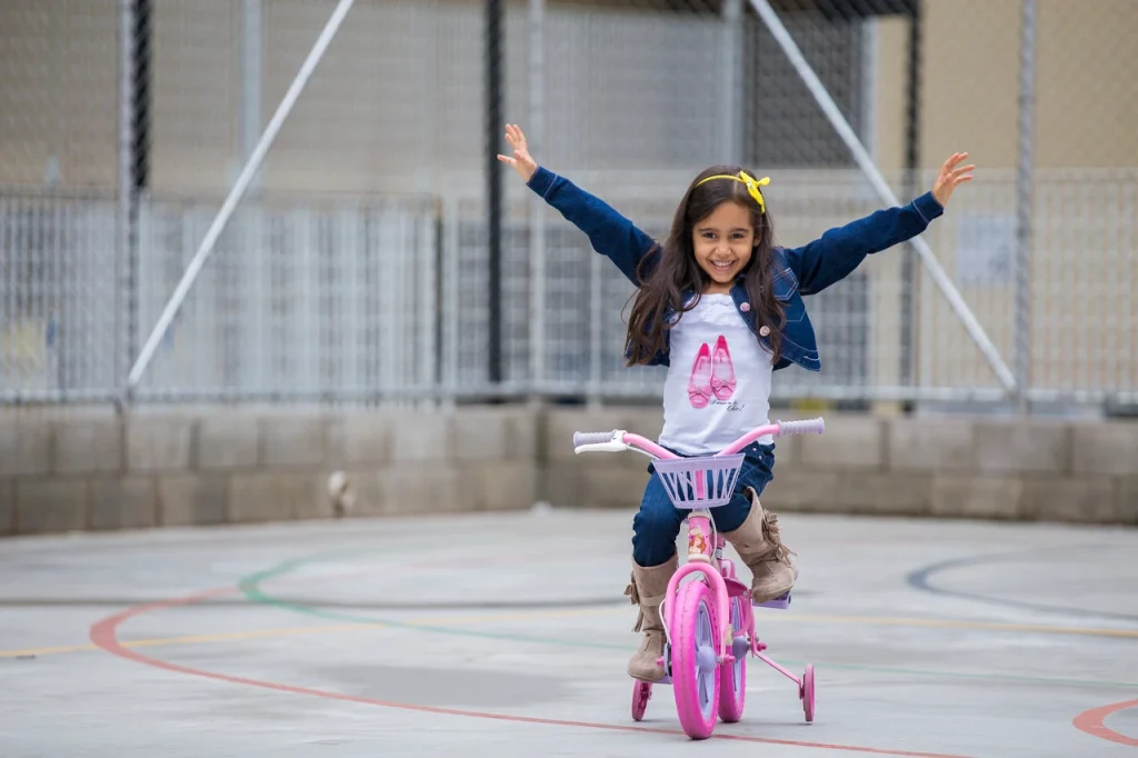 Pige der cykler på en lille pink cykel, som illustrerer et aktivt barn i en informationssektion om type 1 diabetes.
